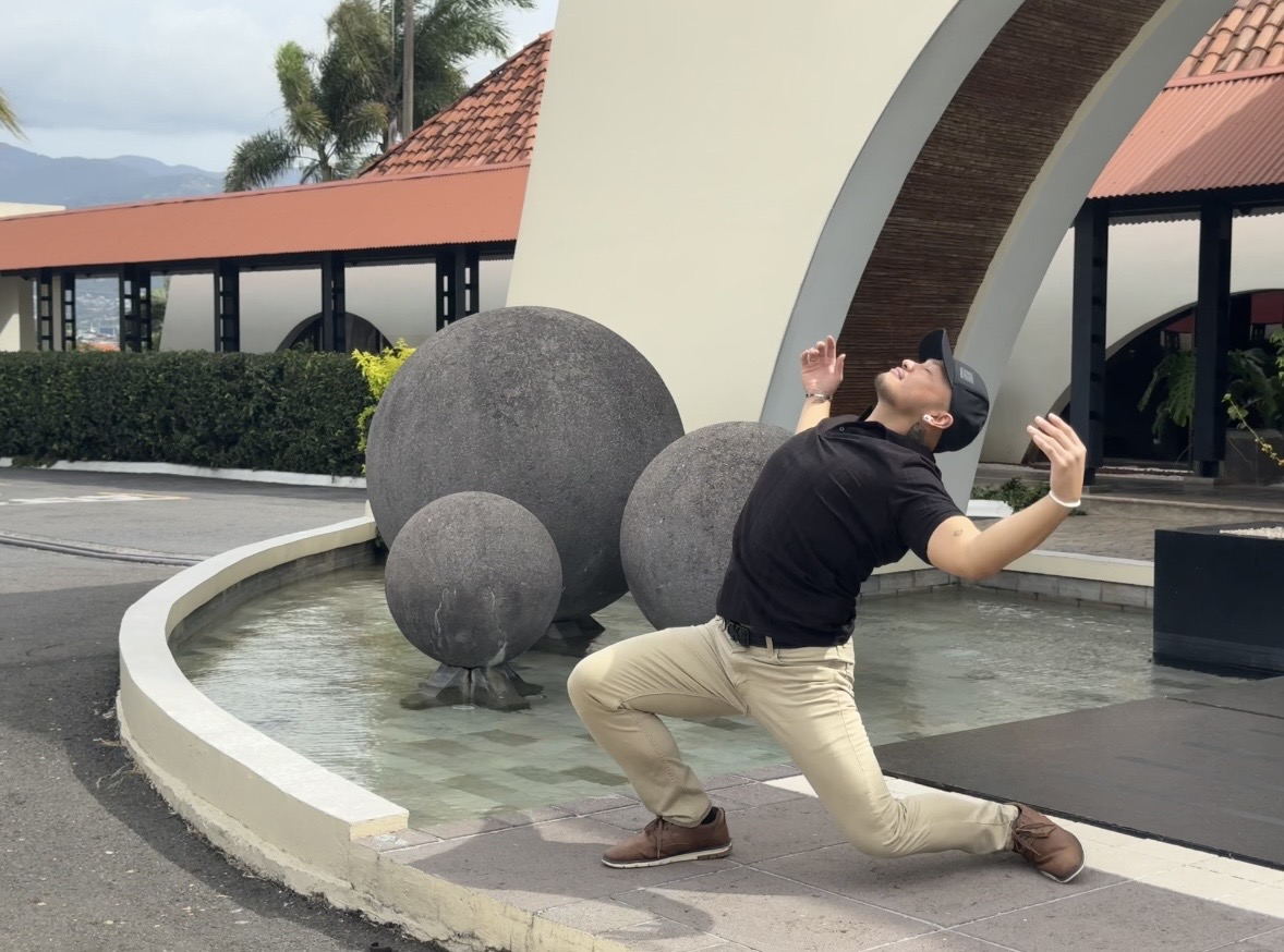 Zano in a deep lunge, arms lifted and head tilted back.