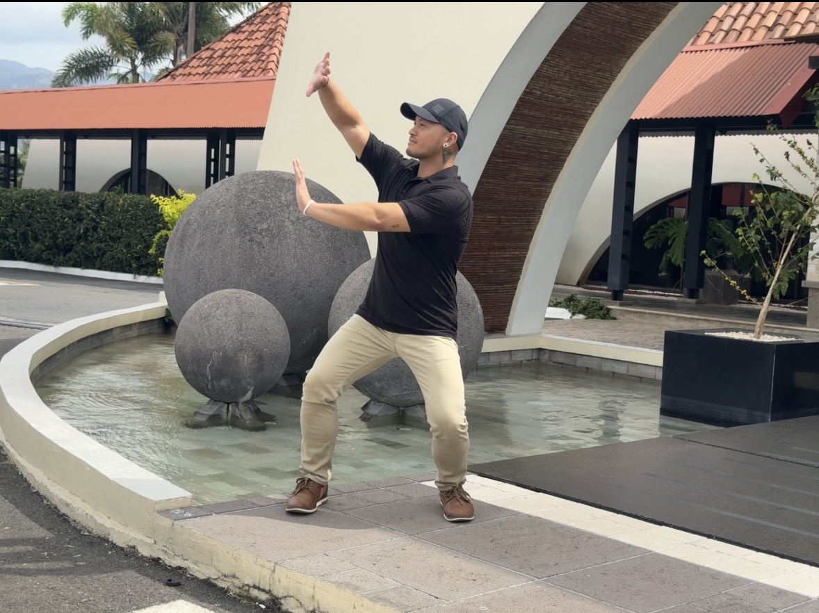 Zano in a grounded qigong stance, hands raised in front of him.